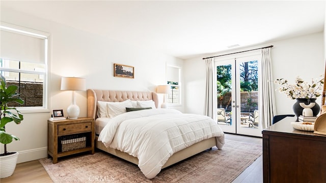 bedroom with baseboards, light wood-style flooring, and access to outside