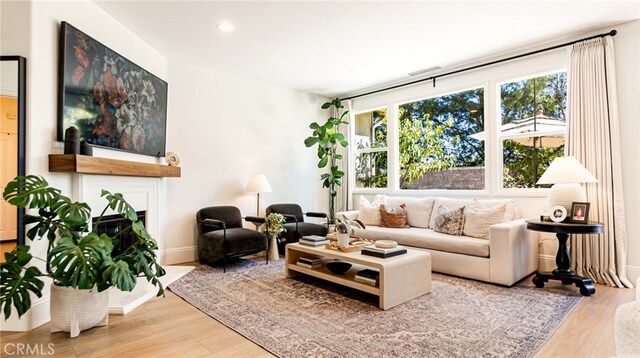 living area with recessed lighting, baseboards, wood finished floors, and a fireplace