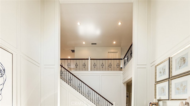 stairs featuring recessed lighting, visible vents, and a decorative wall