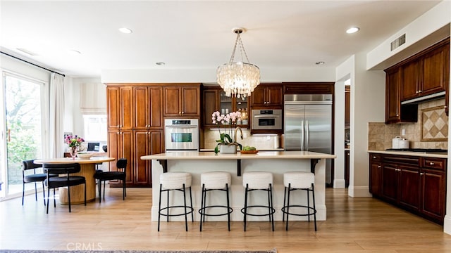 kitchen featuring visible vents, an inviting chandelier, light countertops, appliances with stainless steel finishes, and a kitchen breakfast bar