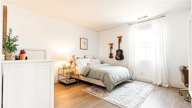 bedroom with baseboards, visible vents, and light wood finished floors