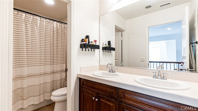 bathroom featuring a sink, visible vents, toilet, and double vanity