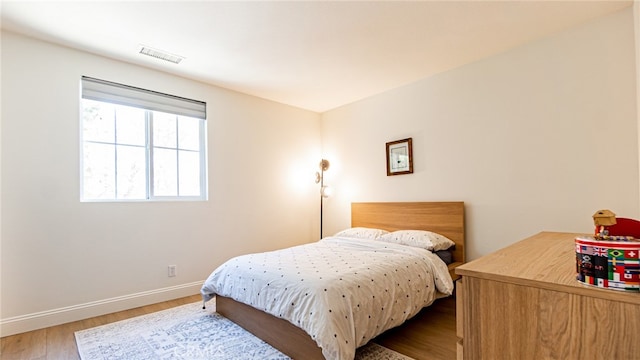 bedroom with visible vents, baseboards, and wood finished floors