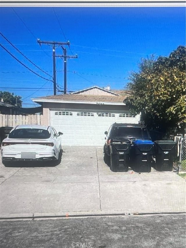 view of front of home featuring an attached garage, concrete driveway, and fence