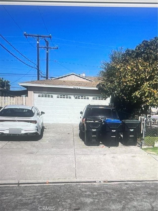 exterior space featuring an attached garage, concrete driveway, and fence