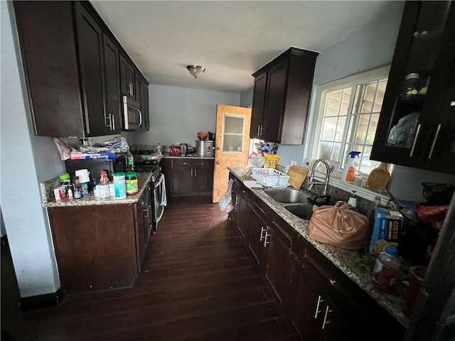 kitchen featuring dark wood-style flooring, light stone countertops, stainless steel range with gas cooktop, and a sink