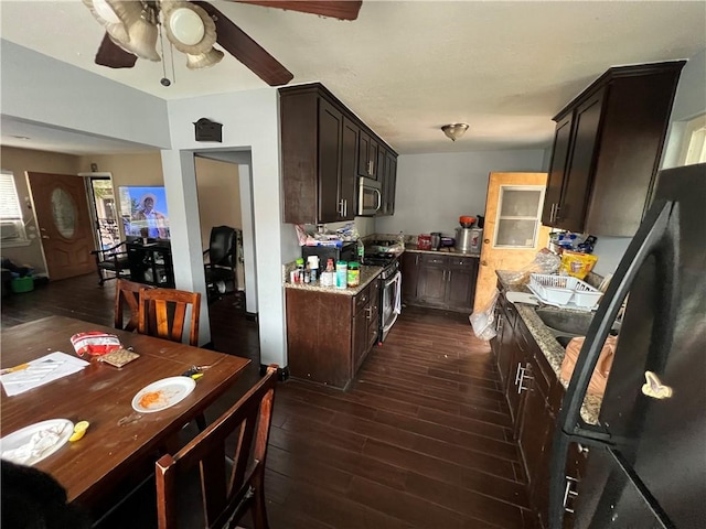 kitchen featuring dark brown cabinets, dark wood-type flooring, light stone counters, stainless steel appliances, and a ceiling fan