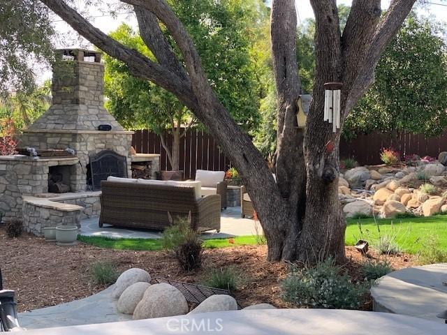 view of yard featuring a patio area, an outdoor living space with a fireplace, and fence