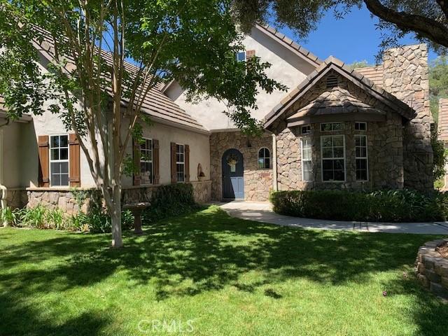 view of front facade featuring a front yard, stone siding, and stucco siding