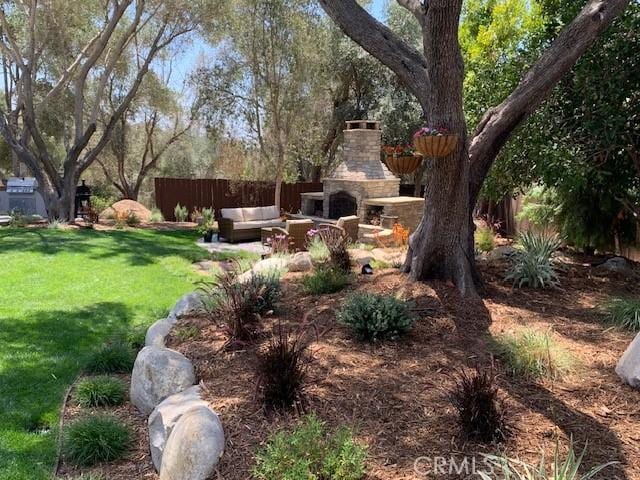 view of yard with an outdoor living space with a fireplace and fence