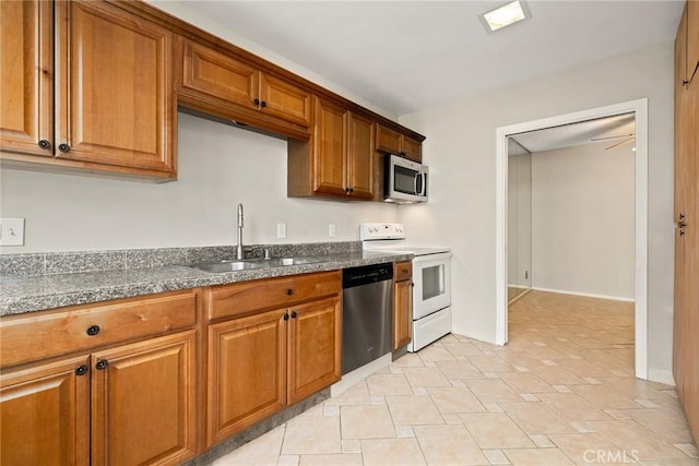 kitchen featuring dark countertops, brown cabinets, appliances with stainless steel finishes, and a sink