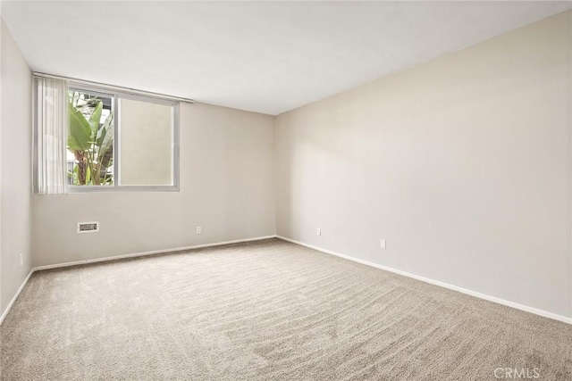 carpeted empty room featuring baseboards and visible vents