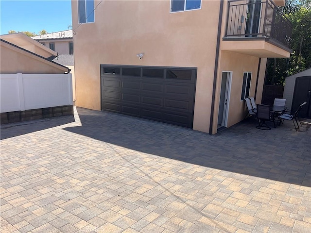 garage with decorative driveway and fence