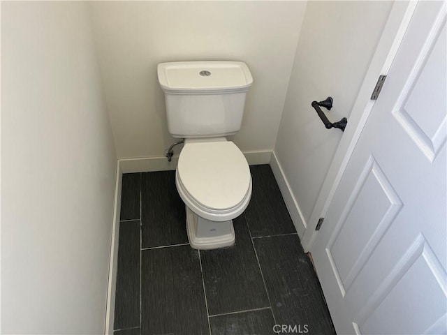 bathroom with toilet, baseboards, and wood finish floors