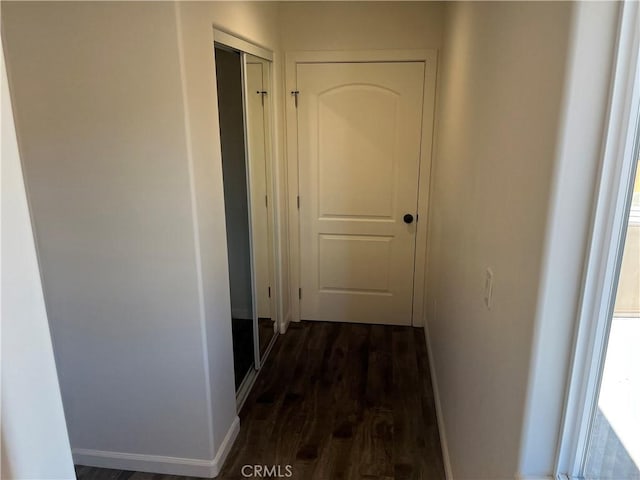 corridor with dark wood-type flooring and baseboards