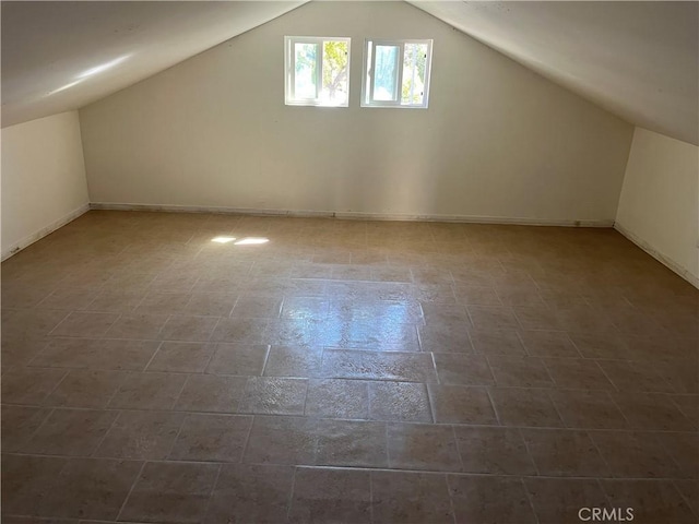 additional living space with baseboards and vaulted ceiling