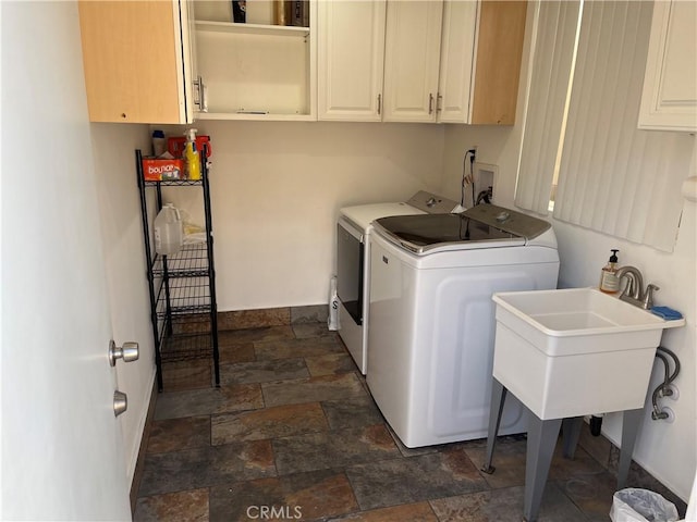 laundry area featuring cabinet space, washing machine and dryer, stone finish flooring, and baseboards