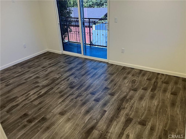 spare room featuring dark wood-type flooring and baseboards