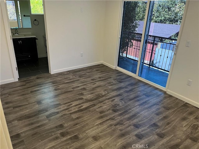 empty room featuring a sink, baseboards, and dark wood-style flooring