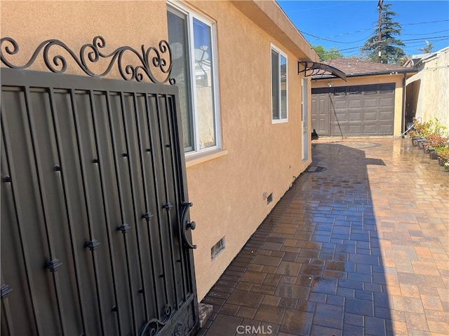 view of property exterior featuring a gate, fence, and stucco siding