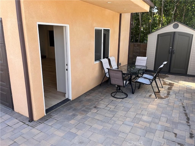 view of patio featuring outdoor dining area, a storage unit, and an outbuilding