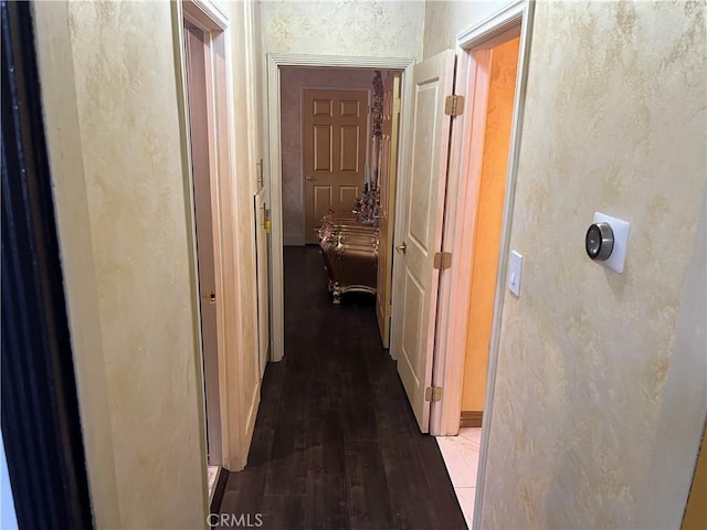 hall with dark wood-style flooring and a textured wall