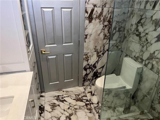 bathroom with tile walls, marble finish floor, toilet, and vanity