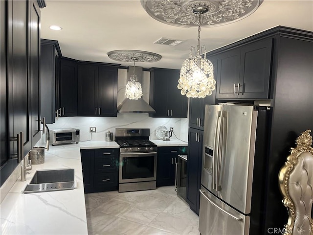 kitchen with visible vents, a sink, appliances with stainless steel finishes, wall chimney exhaust hood, and dark cabinets