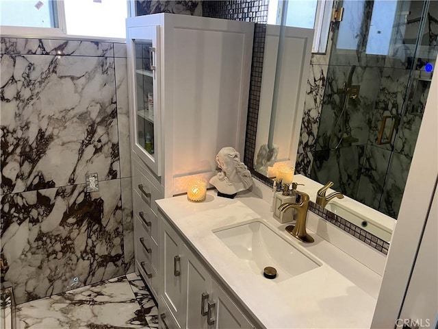 bathroom featuring a marble finish shower, plenty of natural light, marble finish floor, and vanity