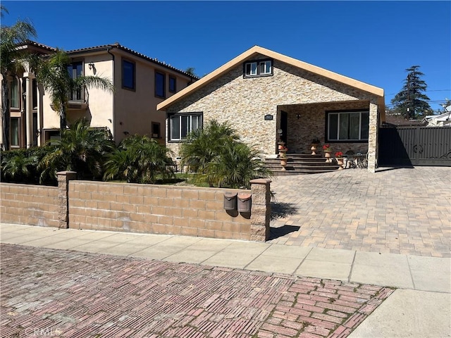 view of front of house featuring stone siding, a fenced front yard, and stucco siding