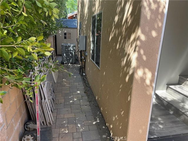 view of home's exterior featuring fence, central AC unit, a storage shed, an outdoor structure, and a patio