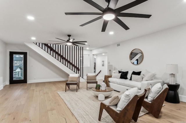 living room with recessed lighting, light wood-type flooring, ceiling fan, and stairs