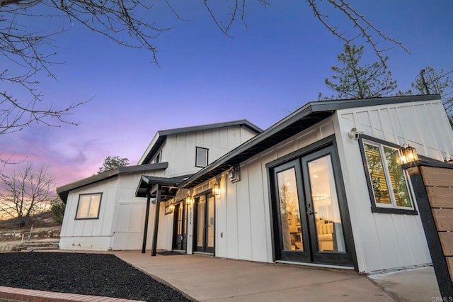 exterior entry at dusk featuring a patio area, french doors, and board and batten siding