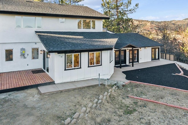 back of property with a patio area, a wooden deck, and a shingled roof