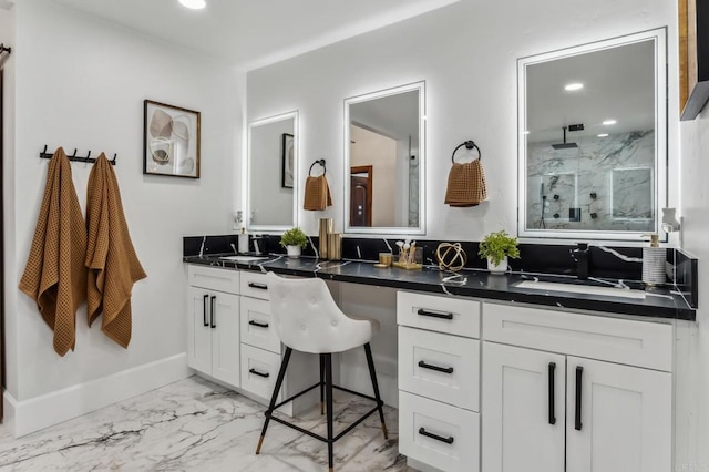 full bath with a sink, marble finish floor, walk in shower, and double vanity