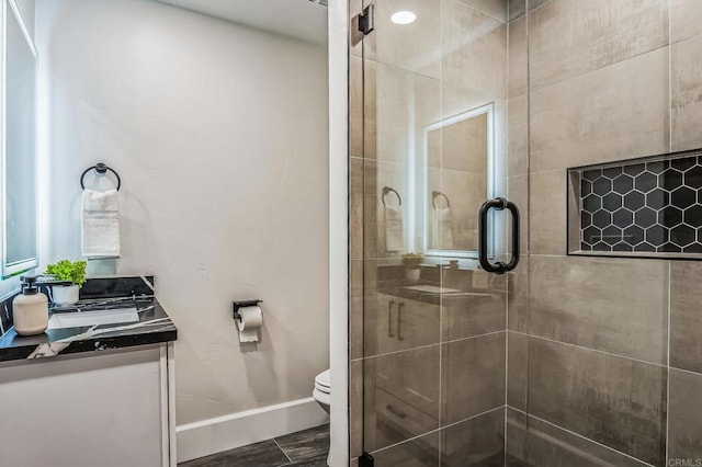 bathroom featuring baseboards, toilet, a stall shower, and vanity