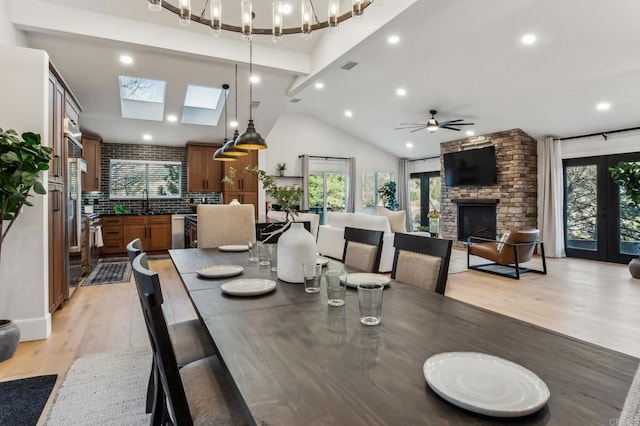 dining area featuring visible vents, high vaulted ceiling, light wood-style flooring, a ceiling fan, and a fireplace