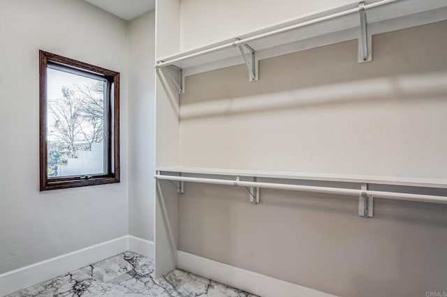 walk in closet featuring marble finish floor