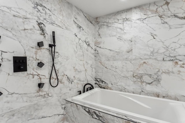 bathroom with tile walls, a tub with marble appearance, and a marble finish shower