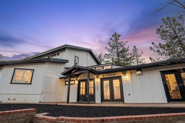 back of house at dusk with french doors and board and batten siding