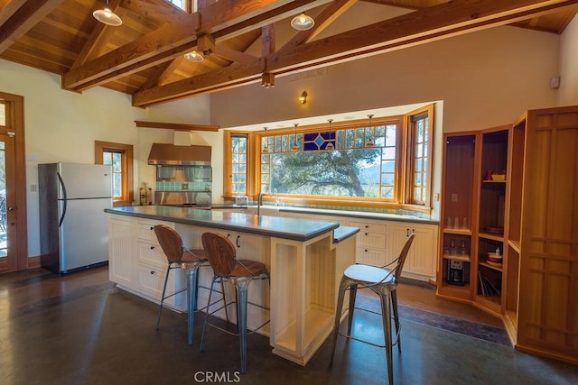 kitchen featuring dark countertops, beamed ceiling, freestanding refrigerator, and a center island