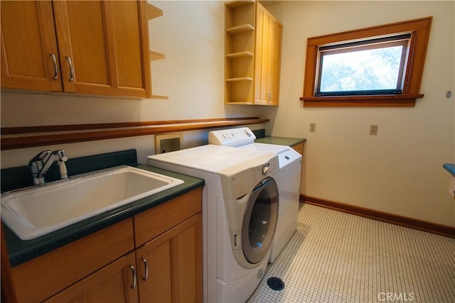 laundry room with light tile patterned floors, baseboards, washing machine and clothes dryer, cabinet space, and a sink