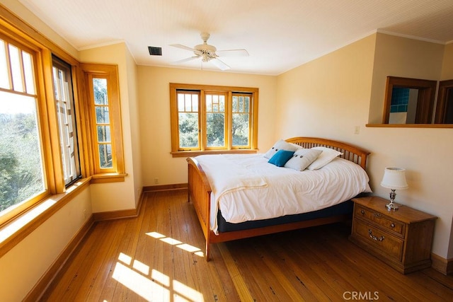 bedroom with hardwood / wood-style floors, multiple windows, baseboards, and ornamental molding