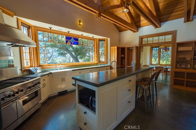 kitchen with beam ceiling, dark countertops, ventilation hood, black microwave, and range with two ovens