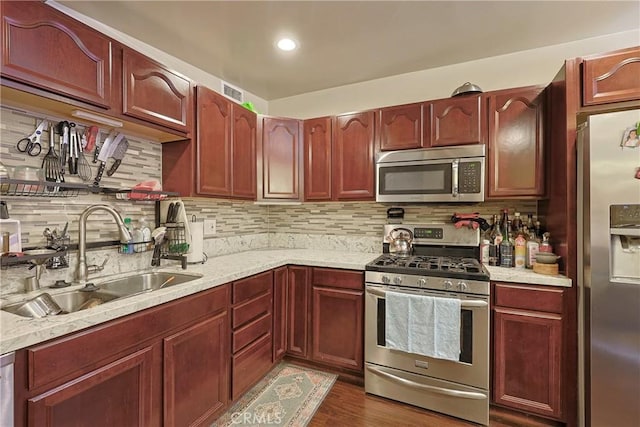 kitchen featuring visible vents, backsplash, appliances with stainless steel finishes, dark wood-style floors, and a sink