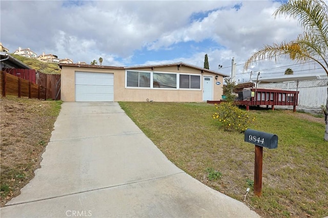 ranch-style home with a front yard, fence, driveway, an attached garage, and stucco siding