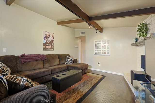 living area with visible vents, a brick fireplace, baseboards, beamed ceiling, and wood finished floors