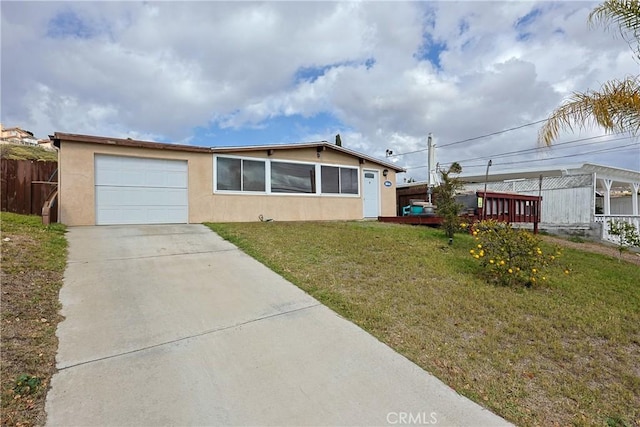 view of front facade featuring a front lawn, concrete driveway, fence, and stucco siding