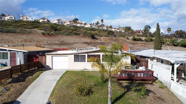 view of front of property featuring a front lawn, fence, stucco siding, driveway, and an attached garage