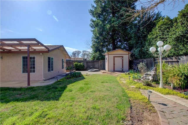 view of yard featuring an outdoor structure, a fenced backyard, a shed, and a patio